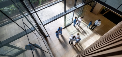 Doctors and patients talking at a busy entrance hall at a hospital - healthcare and medicine concepts