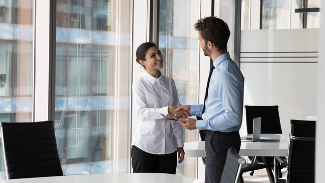 Two diverse confident business man and woman shaking hands