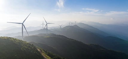 A wind turbine at the top of a mountain on a sunny day